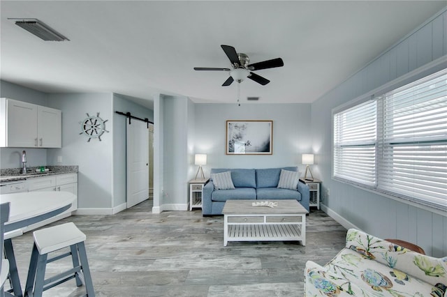 12321 Gulf Blvd, Treasure Island, FL 33706 - living area featuring a barn door, ceiling fan, light wood-type flooring, and baseboards