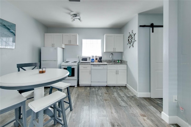 12321 Gulf Blvd, Treasure Island, FL 33706 - kitchen featuring white appliances, a sink, light wood finished floors, white cabinets, and light countertops