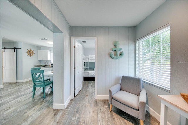 12321 Gulf Blvd, Treasure Island, FL 33706 - sitting room featuring light wood finished floors, baseboards, and a barn door