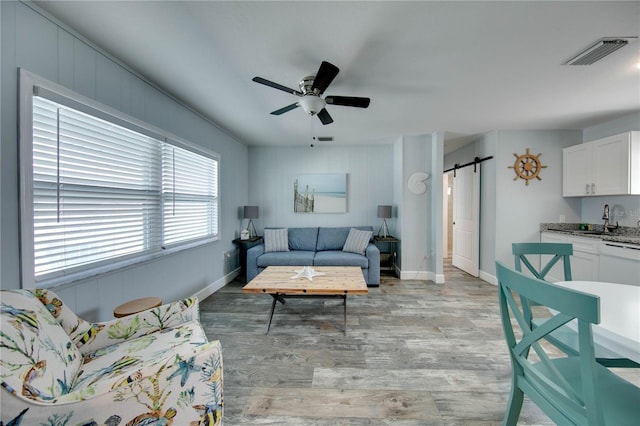 12321 Gulf Blvd, Treasure Island, FL 33706 - living area with a barn door, light wood-style floors, a ceiling fan, and baseboards