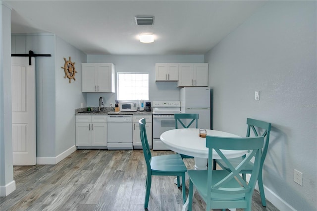 12321 Gulf Blvd, Treasure Island, FL 33706 - kitchen with white appliances, light wood-style floors, white cabinetry, a sink, and baseboards