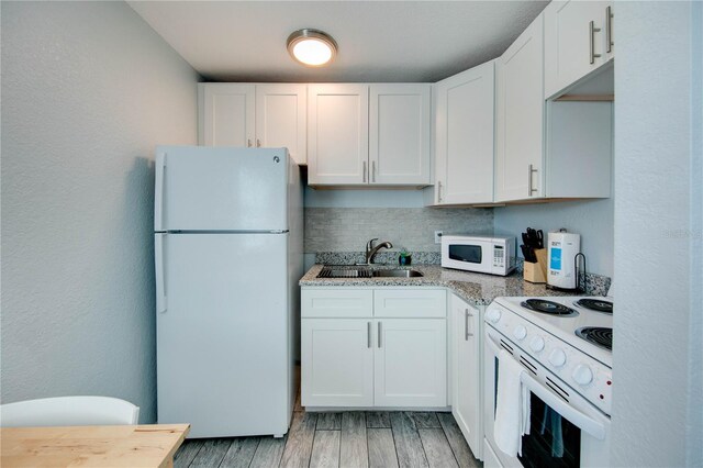 12321 Gulf Blvd, Treasure Island, FL 33706 - kitchen with white appliances, a sink, white cabinets, light wood-style flooring, and light stone countertops