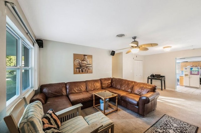 living room with a wealth of natural light, ceiling fan, and light carpet