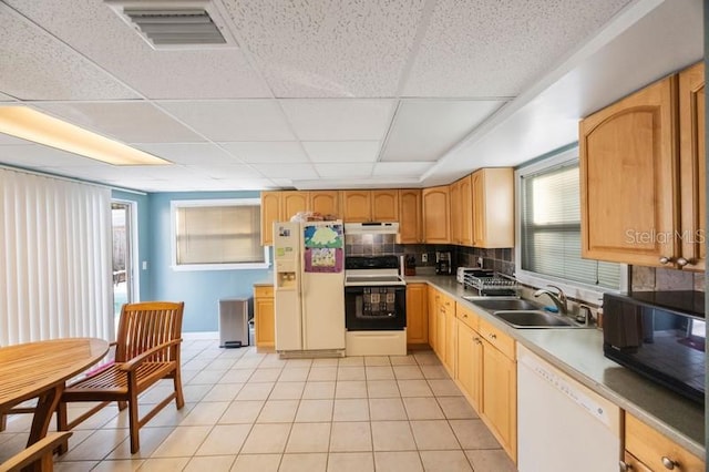 kitchen with a paneled ceiling, tasteful backsplash, white appliances, sink, and light tile patterned floors