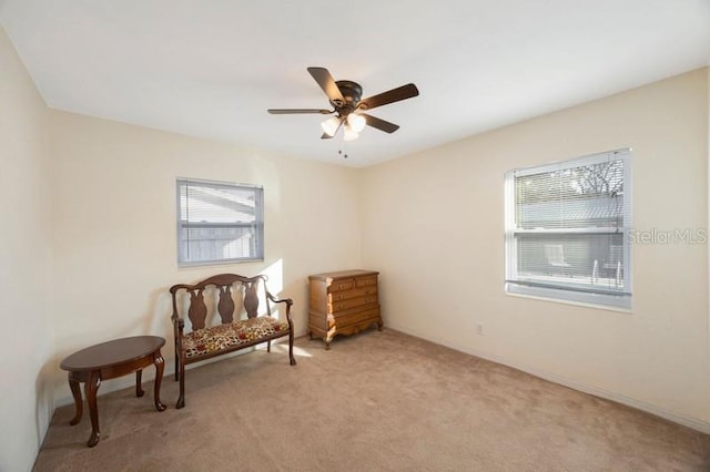 living area with light colored carpet and ceiling fan