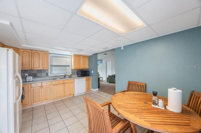 kitchen with light brown cabinets, white appliances, a paneled ceiling, and backsplash