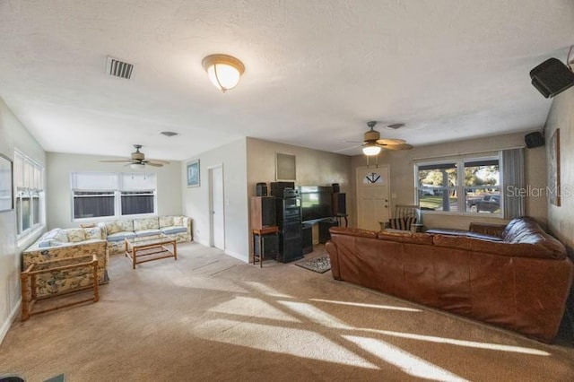 carpeted living room featuring ceiling fan and a textured ceiling