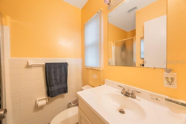 bathroom featuring vanity, toilet, tile walls, and walk in shower