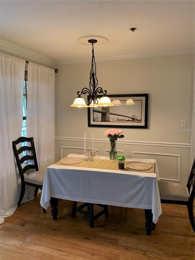 dining room with crown molding, hardwood / wood-style floors, and a notable chandelier