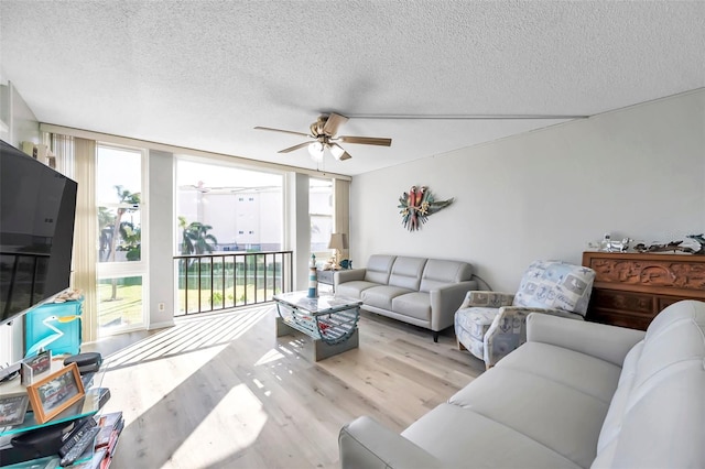 living room featuring a textured ceiling, light hardwood / wood-style floors, and ceiling fan