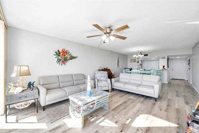 living room with ceiling fan with notable chandelier, light wood-type flooring, and a textured ceiling