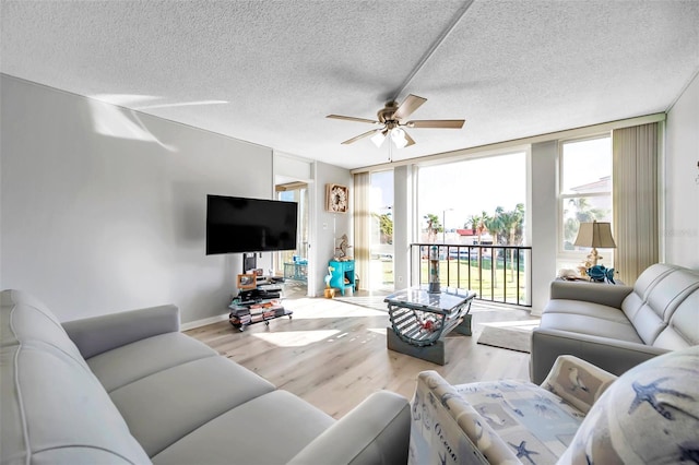 living room with ceiling fan, floor to ceiling windows, light wood-type flooring, and a textured ceiling