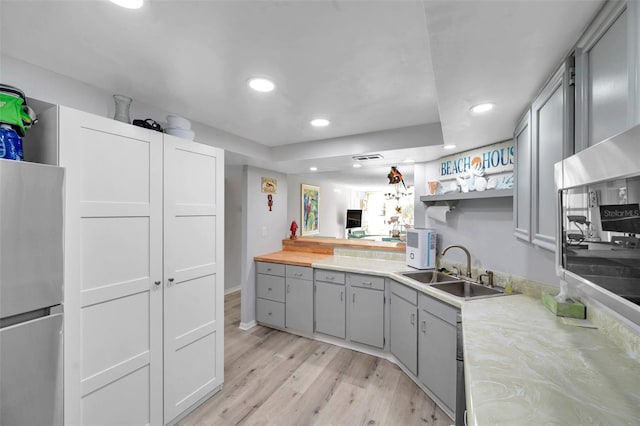 kitchen with gray cabinets, stainless steel fridge, light hardwood / wood-style floors, and sink