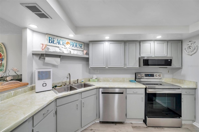 kitchen with stainless steel appliances, light hardwood / wood-style flooring, gray cabinetry, and sink