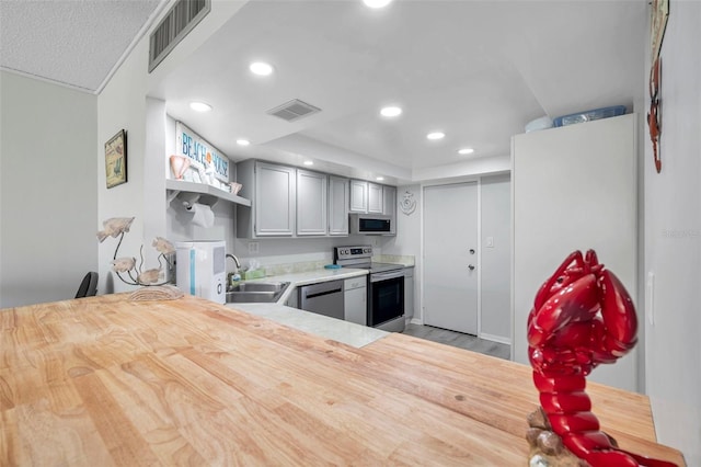 kitchen featuring light wood-type flooring, stainless steel appliances, gray cabinetry, and sink