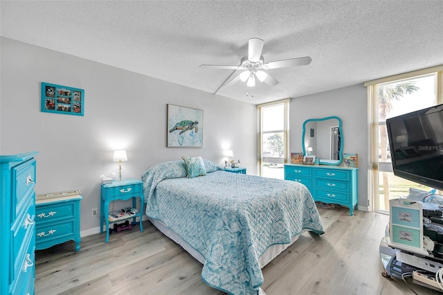 bedroom featuring a textured ceiling, light wood-type flooring, and ceiling fan