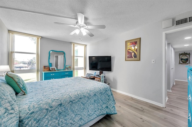 bedroom featuring ceiling fan, light hardwood / wood-style floors, and a textured ceiling