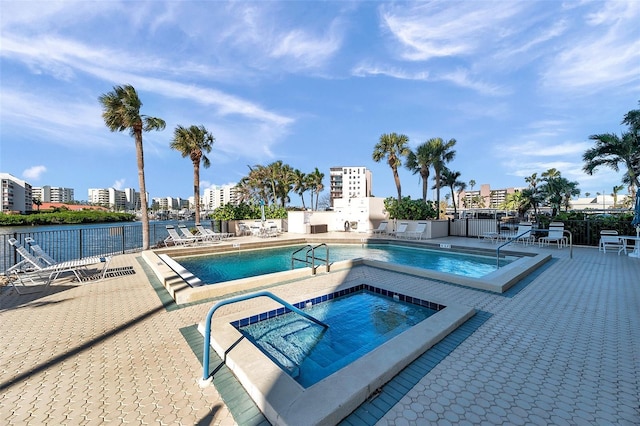 view of swimming pool featuring a patio area, a water view, and a hot tub