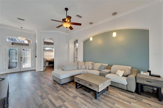 living room with hardwood / wood-style floors, ceiling fan with notable chandelier, ornamental molding, and french doors