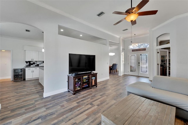 living room featuring french doors, wine cooler, hardwood / wood-style flooring, ceiling fan, and ornamental molding