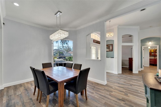 dining space with hardwood / wood-style floors, a notable chandelier, and ornamental molding