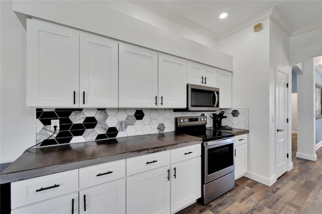 kitchen with stainless steel appliances, white cabinetry, dark hardwood / wood-style floors, and ornamental molding