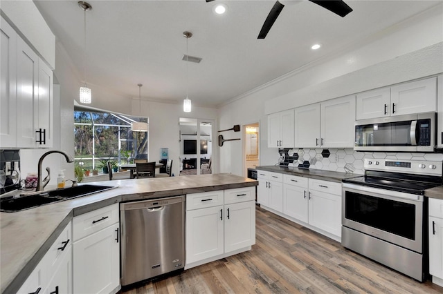 kitchen with white cabinets, decorative light fixtures, sink, and stainless steel appliances