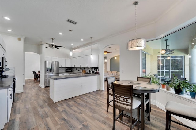 kitchen featuring appliances with stainless steel finishes, hardwood / wood-style floors, pendant lighting, white cabinets, and ornamental molding