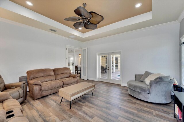 living room featuring ceiling fan, french doors, crown molding, wood-type flooring, and a tray ceiling