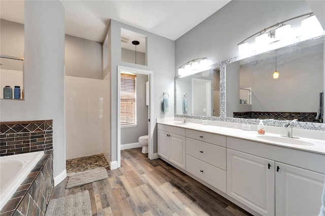 full bathroom with wood-type flooring, vanity, shower with separate bathtub, and toilet