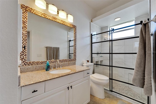 bathroom with tile patterned floors, vanity, toilet, and tiled shower