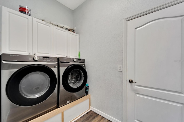 clothes washing area featuring cabinets, separate washer and dryer, and dark hardwood / wood-style floors