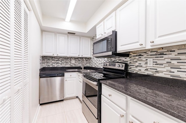 kitchen featuring light tile patterned floors, white cabinetry, backsplash, and appliances with stainless steel finishes