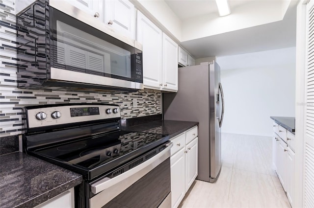 kitchen with backsplash, white cabinetry, dark stone counters, and stainless steel appliances