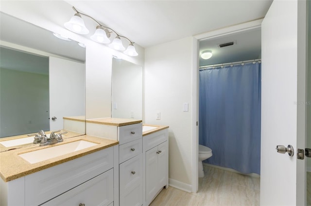 bathroom with vanity, toilet, and wood-type flooring