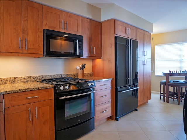 kitchen with light stone countertops, light tile patterned floors, and black appliances