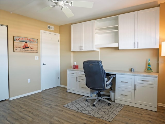 home office featuring ceiling fan, built in desk, and dark wood-type flooring