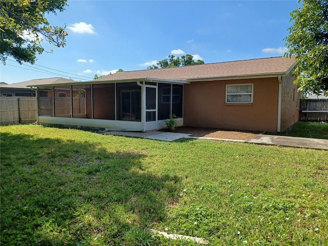 back of house featuring a sunroom and a lawn