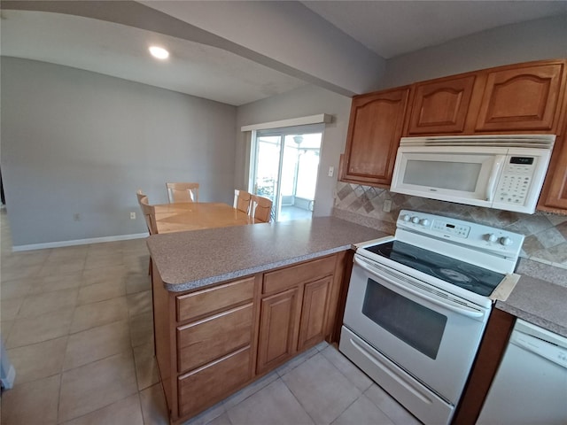 kitchen featuring white appliances, kitchen peninsula, decorative backsplash, and light tile patterned floors