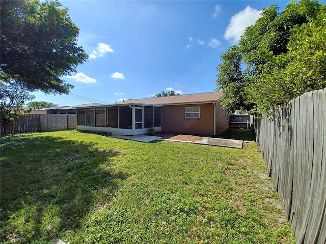 back of house with a lawn, a sunroom, and a patio area