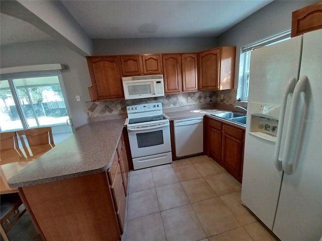 kitchen featuring white appliances, kitchen peninsula, sink, and backsplash