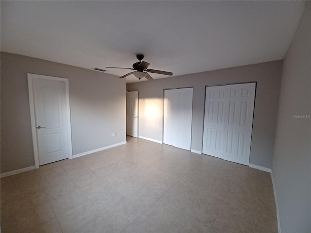 unfurnished bedroom featuring two closets and ceiling fan