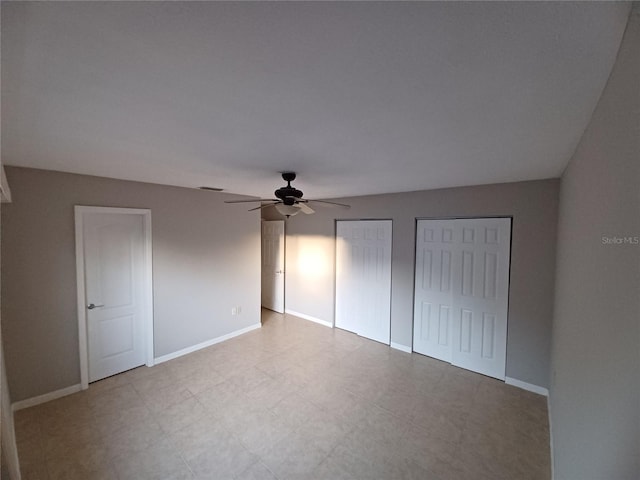 unfurnished bedroom with multiple closets and ceiling fan