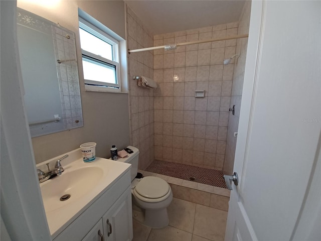 bathroom with vanity, tile patterned flooring, toilet, and tiled shower