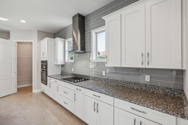 kitchen with black electric cooktop, white cabinetry, wall chimney exhaust hood, and dark stone countertops