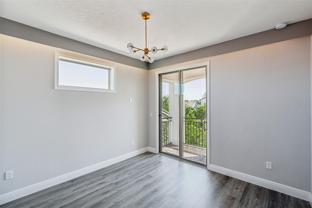 unfurnished room with a notable chandelier, dark hardwood / wood-style flooring, and a textured ceiling