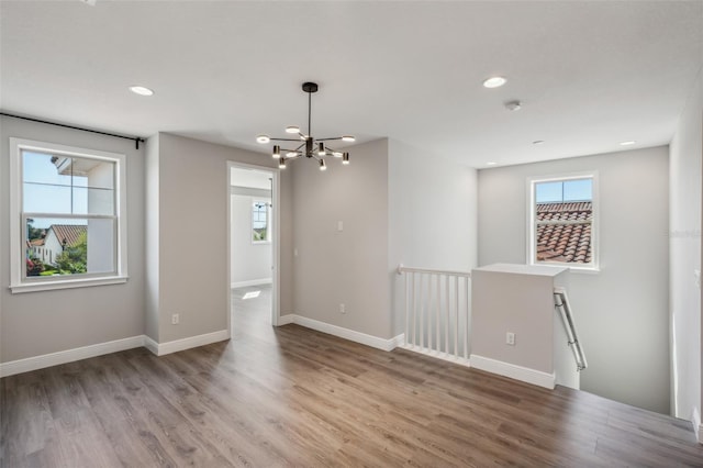 unfurnished room featuring a notable chandelier and light hardwood / wood-style floors