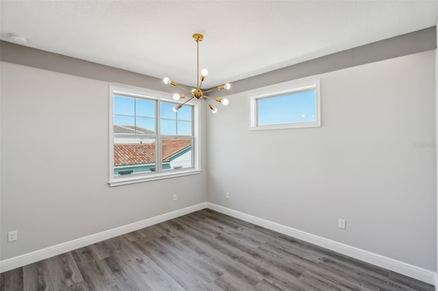 spare room featuring dark hardwood / wood-style flooring and a chandelier