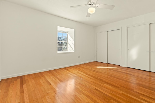 unfurnished bedroom with ceiling fan, light hardwood / wood-style flooring, and two closets