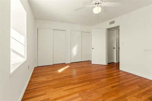 unfurnished bedroom featuring multiple closets, ceiling fan, and light hardwood / wood-style floors